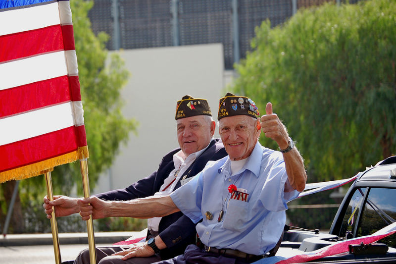 Two veterans (VFW) holding US flags in a parade